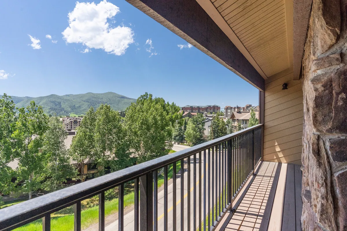 A tranquil balcony scene with a railing overlooking a picturesque mountain and valley view, perfect for enjoying morning coffee or relaxing after a day outdoors.