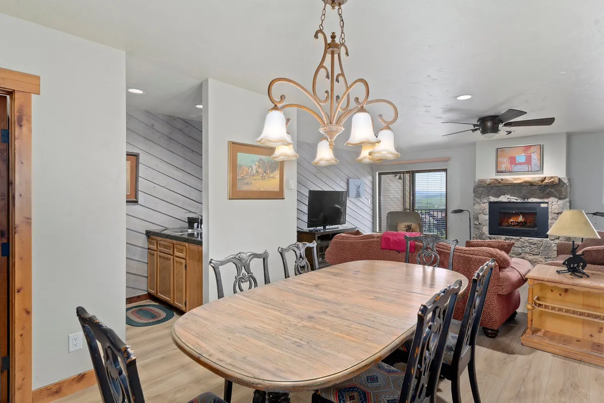 A cozy interior scene featuring a dining table, elegant chandelier, fireplace, and plush seating. The room radiates warmth, ideal for gatherings, family dinners, and relaxation after a day of exploring regardless of the season.