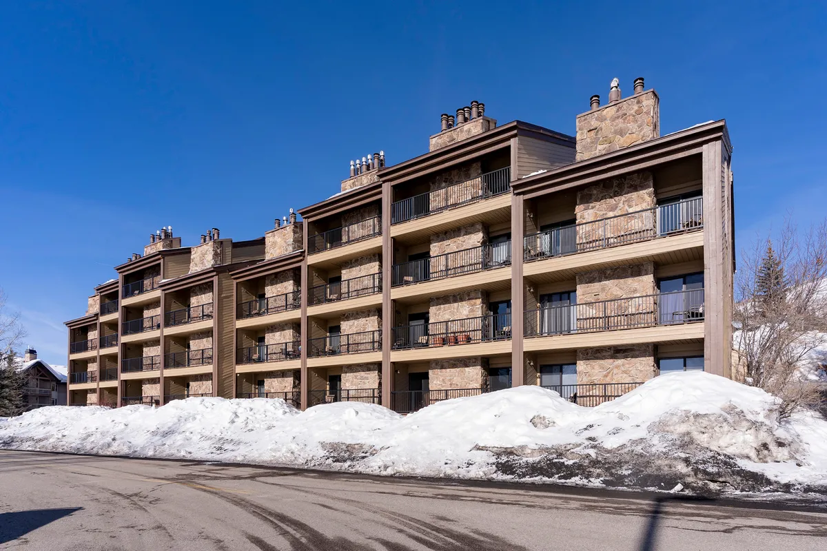A cozy exterior view of the property with stone facades, balconies, chimneys, and a snow-blanketed ground. The image suggests easy access to skiing and other winter sports, and hints at comfortable evenings by the fire after a day outdoors.