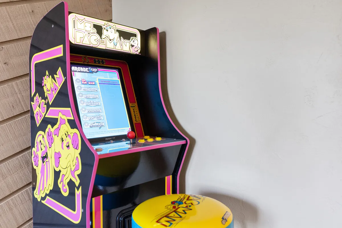 A close-up of a Ms. Pac-Man arcade machine with a colorful arcade stool, evoking nostalgia and excitement for playful gaming sessions.