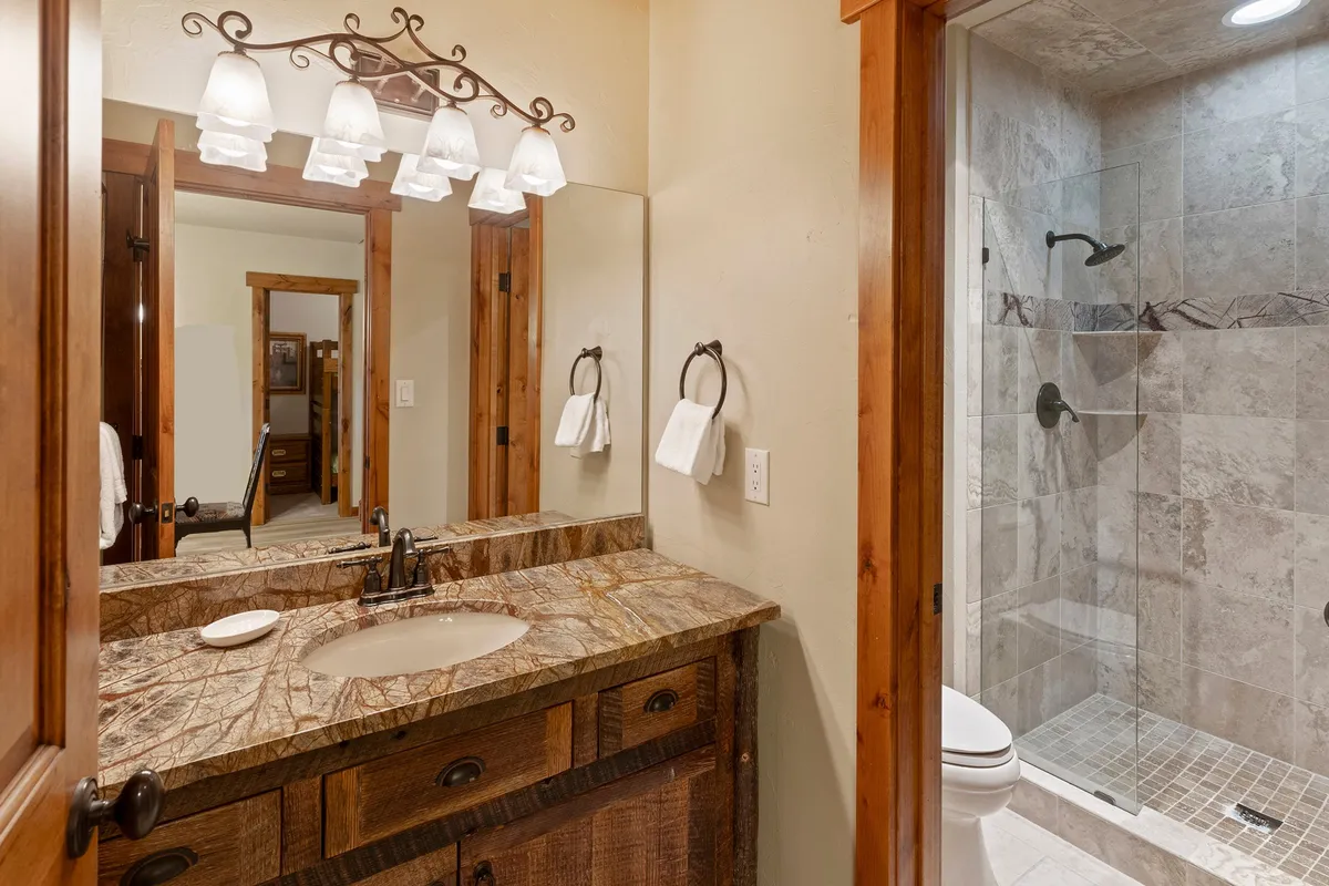 A spacious bathroom with a granite vanity, large mirror, and a sleek walk-in shower. The inviting setting is ideal for refreshing after outdoor adventures or preparing for the day ahead.