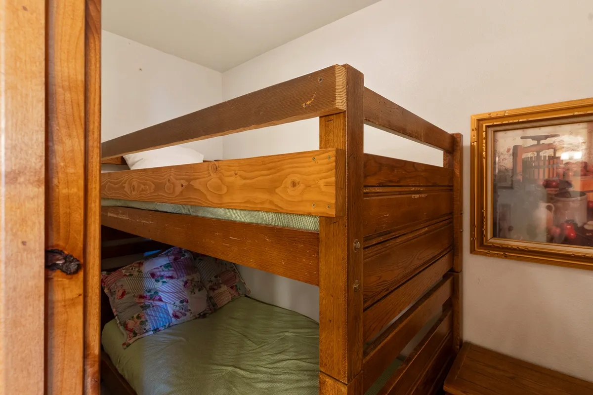 A cozy bedroom featuring a bunk bed adorned with colorful pillows and playful framed artwork on the wall, inviting children to sleep, read, or unwind in a cheerful space.